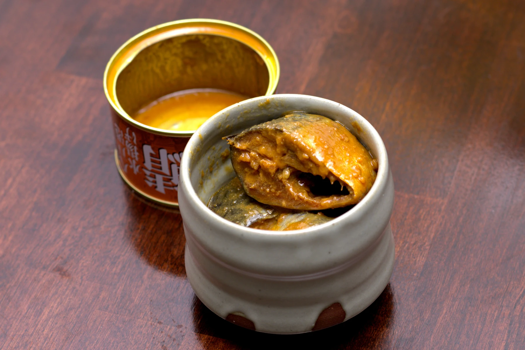 Mackerel out of the can and served in a separate dish covered in sauce.