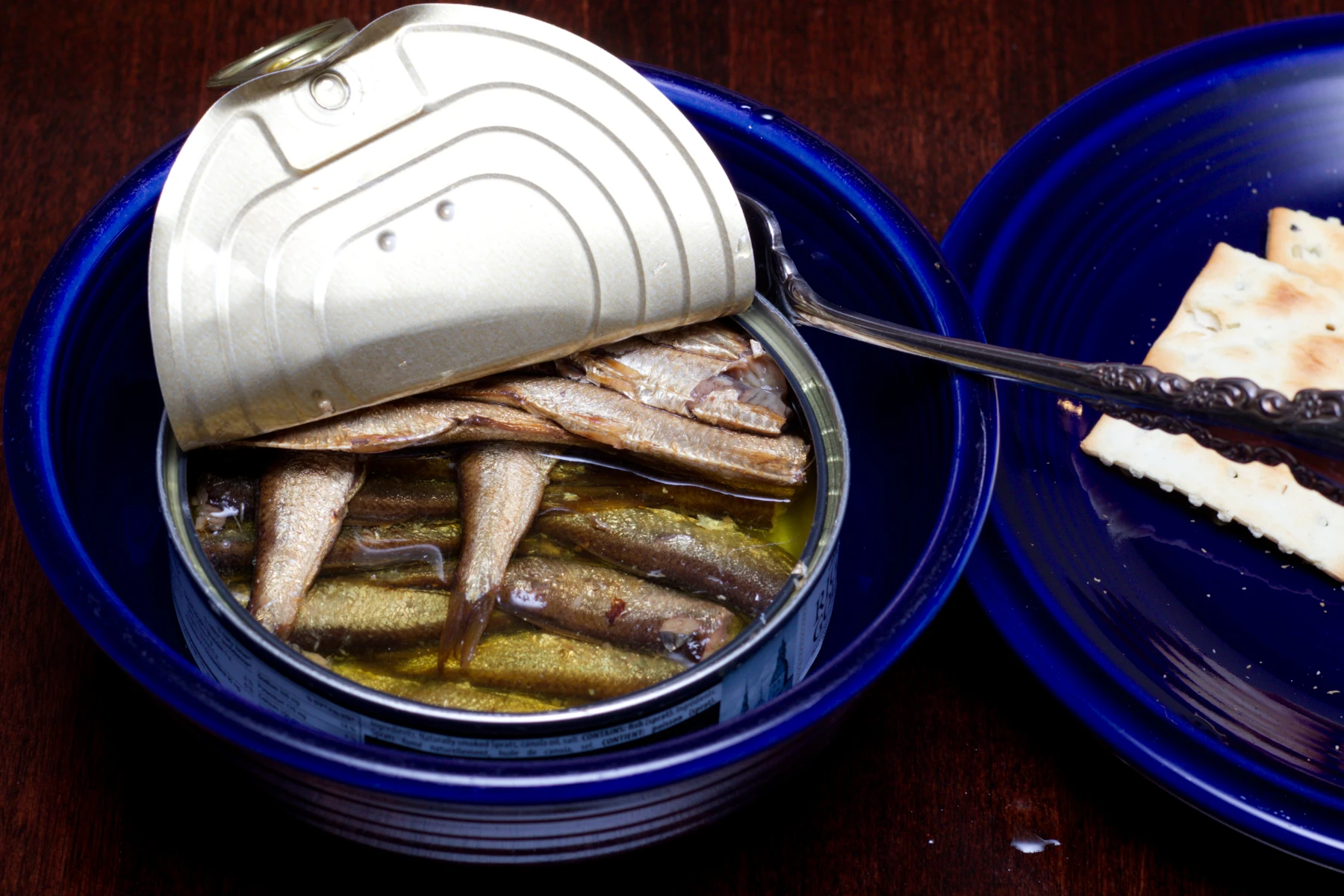 A half-eaten can of sprats with oil.